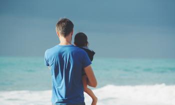 Dad and child by the ocean surf