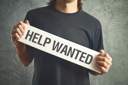 Guy holding a "help wanted" sign