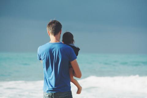 Dad and child by the ocean surf