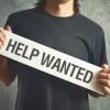 Guy holding a "help wanted" sign